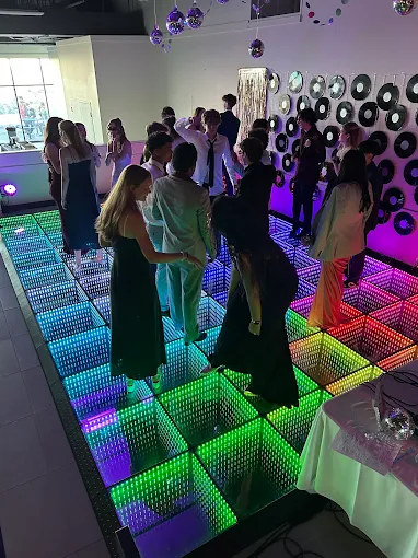 Guests on a multicoloured LED floor beside a record-decorated wall