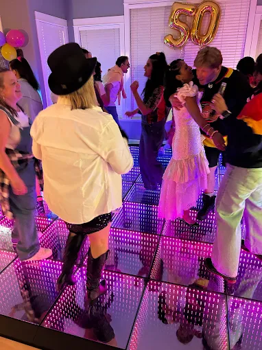Guests dancing on a pink LED floor at a 50th birthday party
