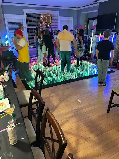 A birthday party with guests gathered around an illuminated dance floor