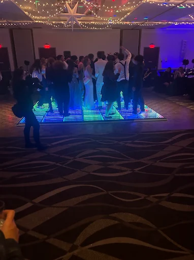 Guests dancing on a multicoloured LED floor beneath string lights and a hanging star